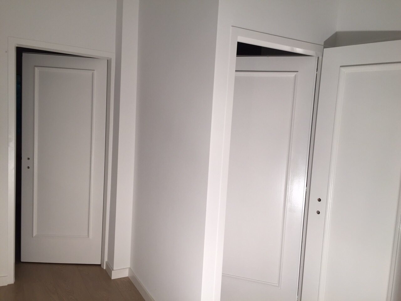 Portes intérieures blanches à panneaux moulurés posées dans un couloir