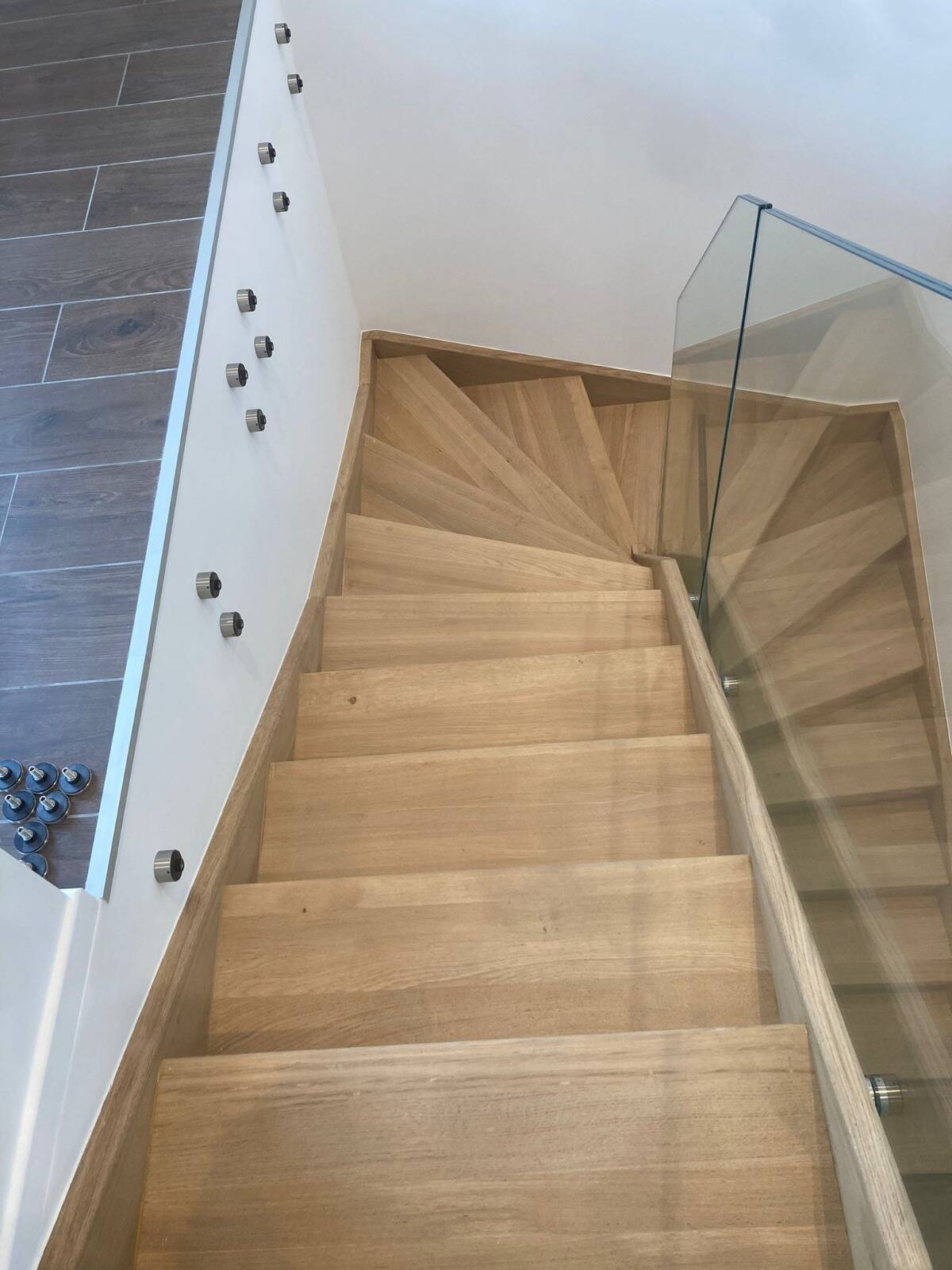 Escalier intérieur en bois avec garde-corps en verre vu depuis l'étage