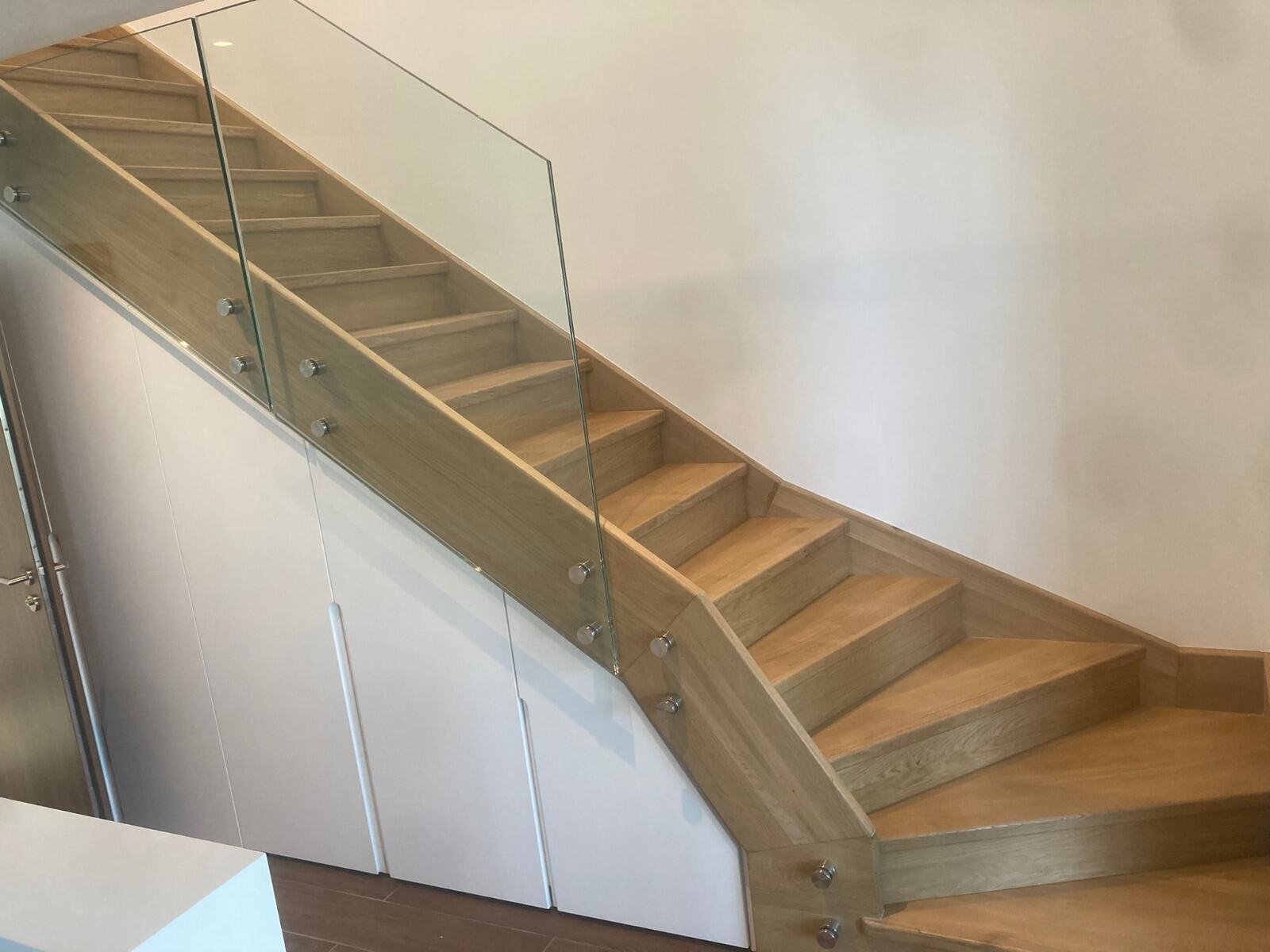 Escalier en bois avec garde-corps en verre fixé sur un limon blanc