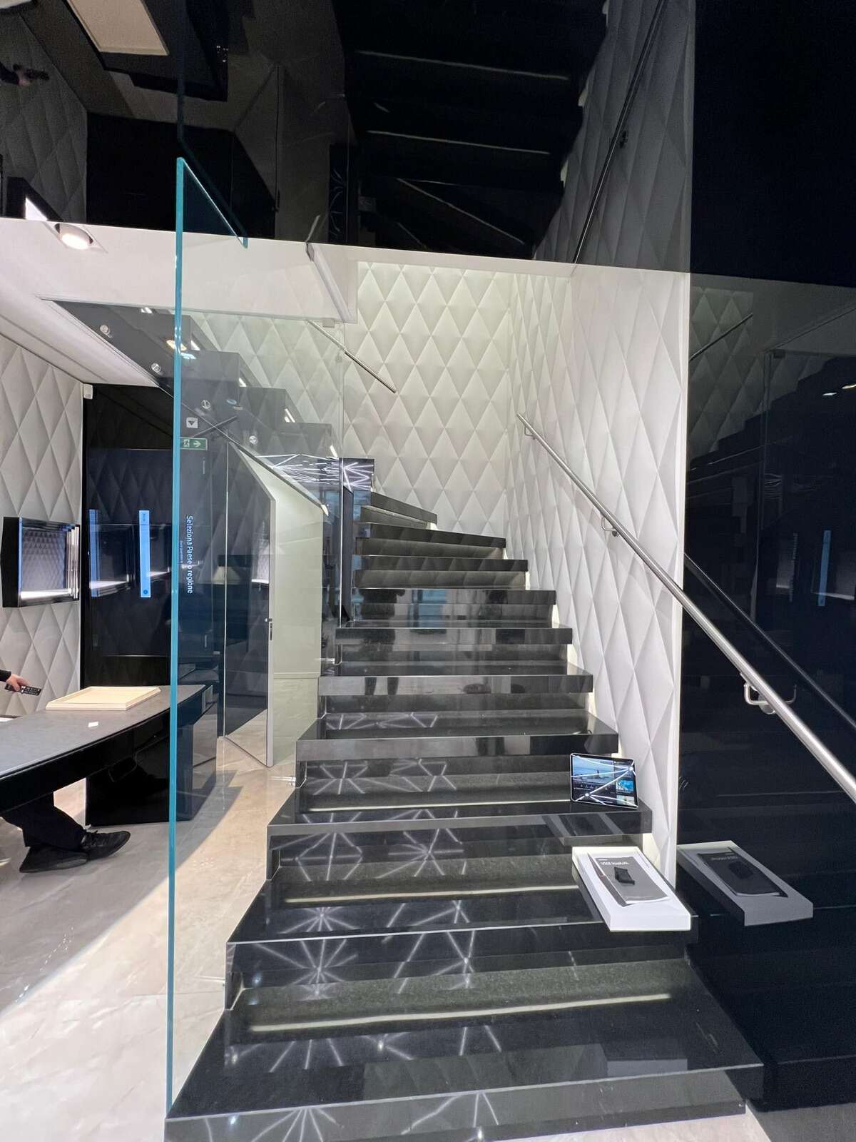 Escalier de magasin avec mur capitonné blanc et garde-corps en verre