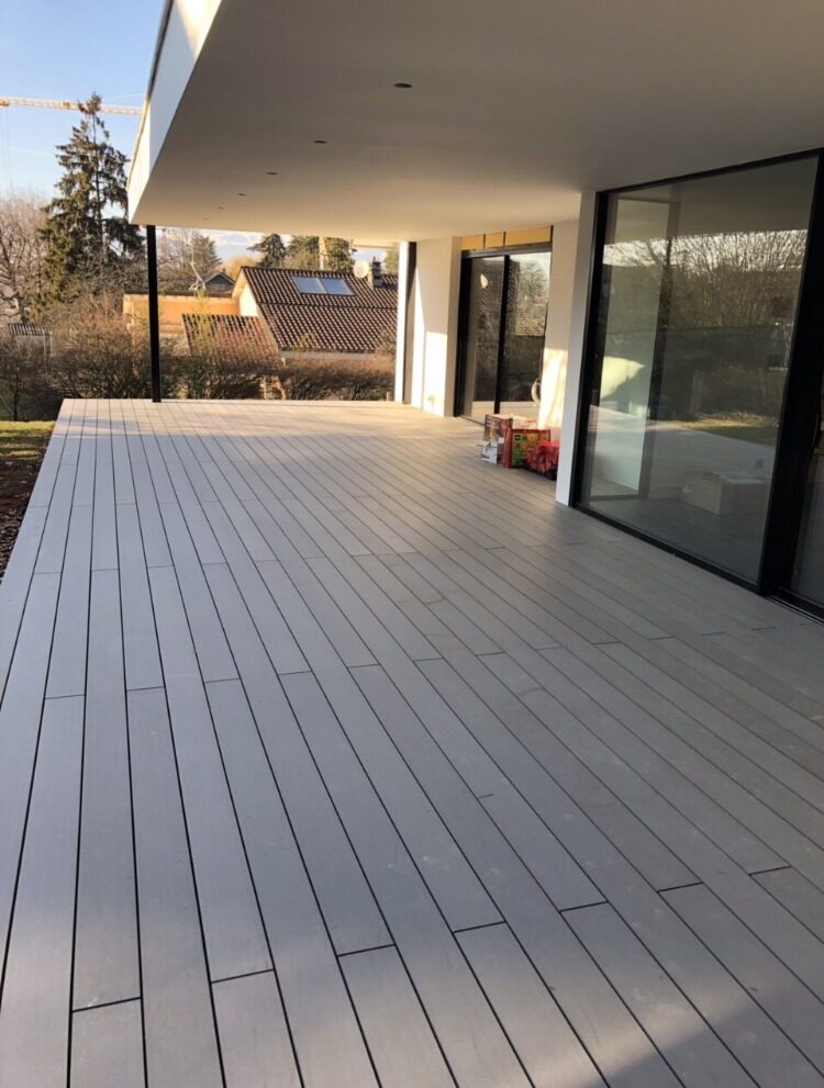 Grande terrasse en lames composites devant les baies vitrées d'une villa