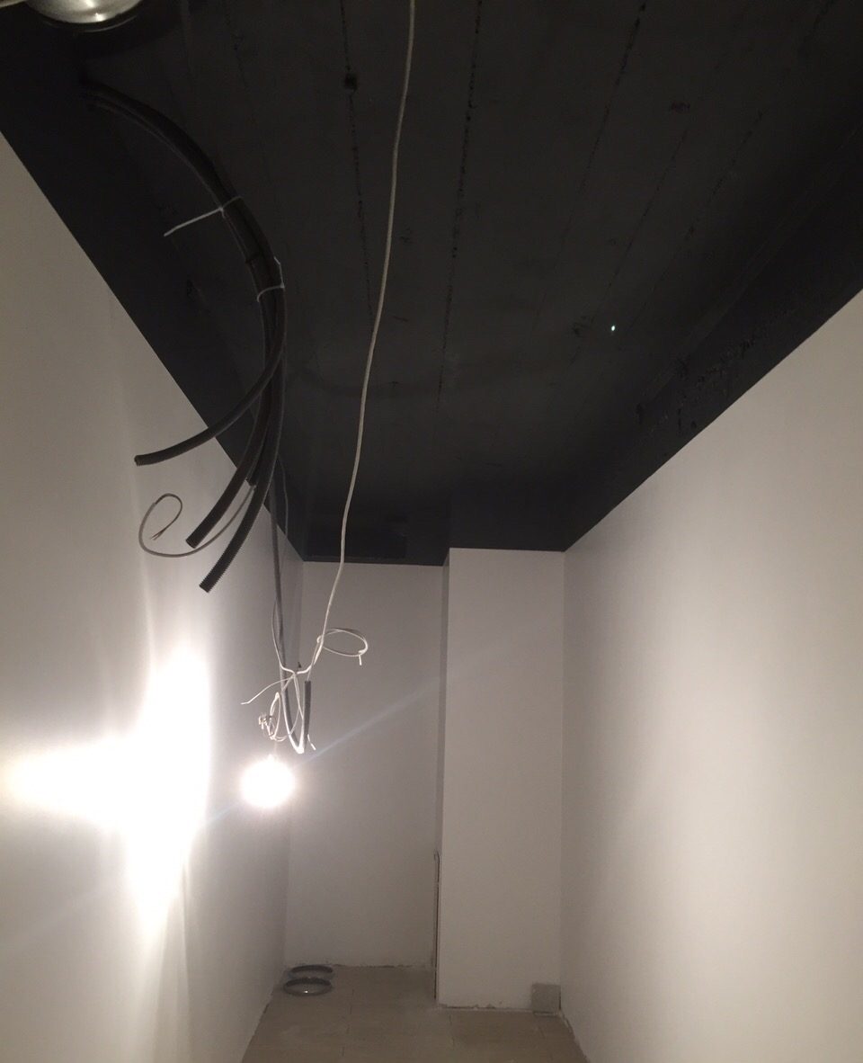 Câbles et gaines en attente de raccordement au plafond d'un couloir de local professionnel à Genève