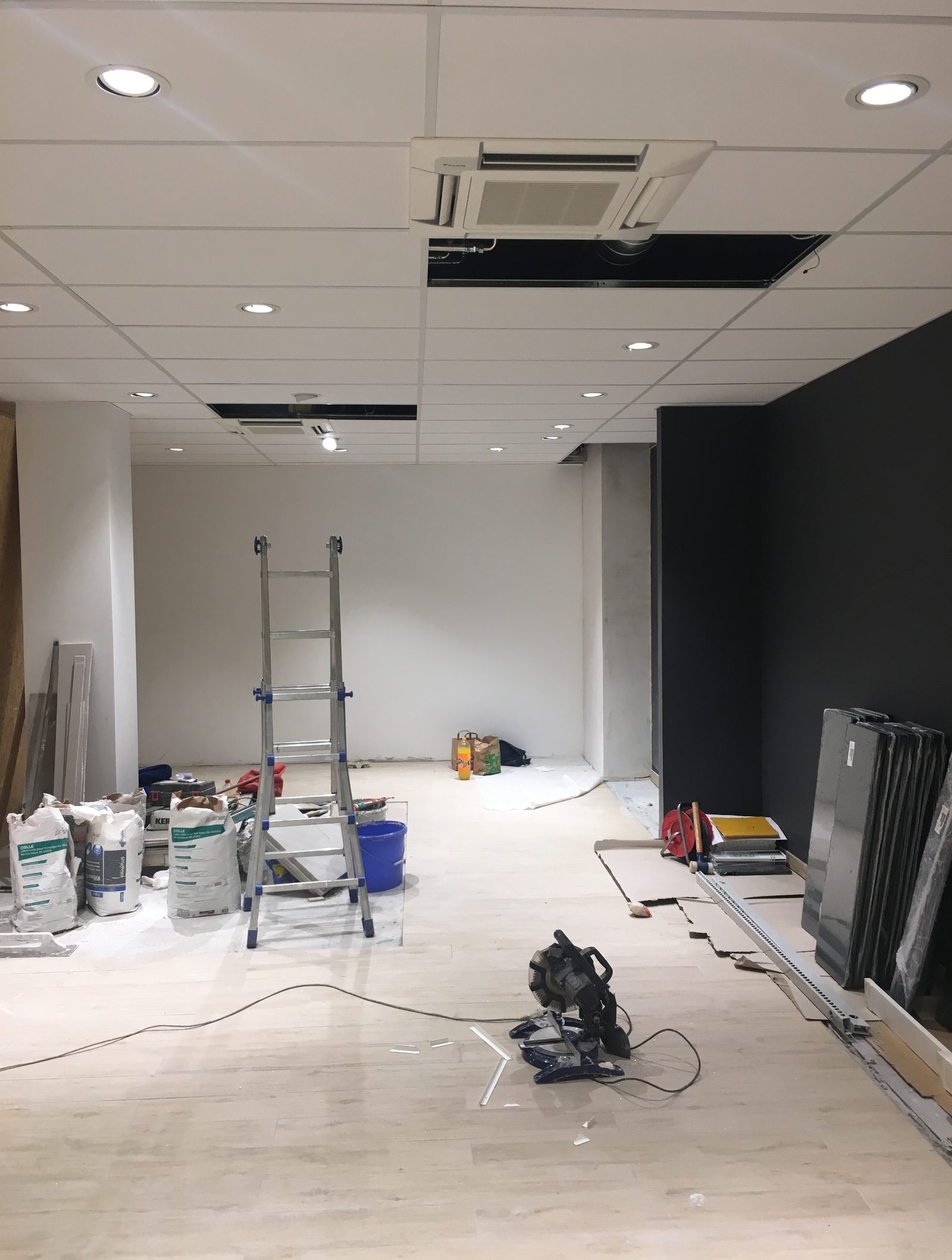 Chantier d'aménagement d'un local commercial à Genève, sol protégé et faux-plafond en cours de pose